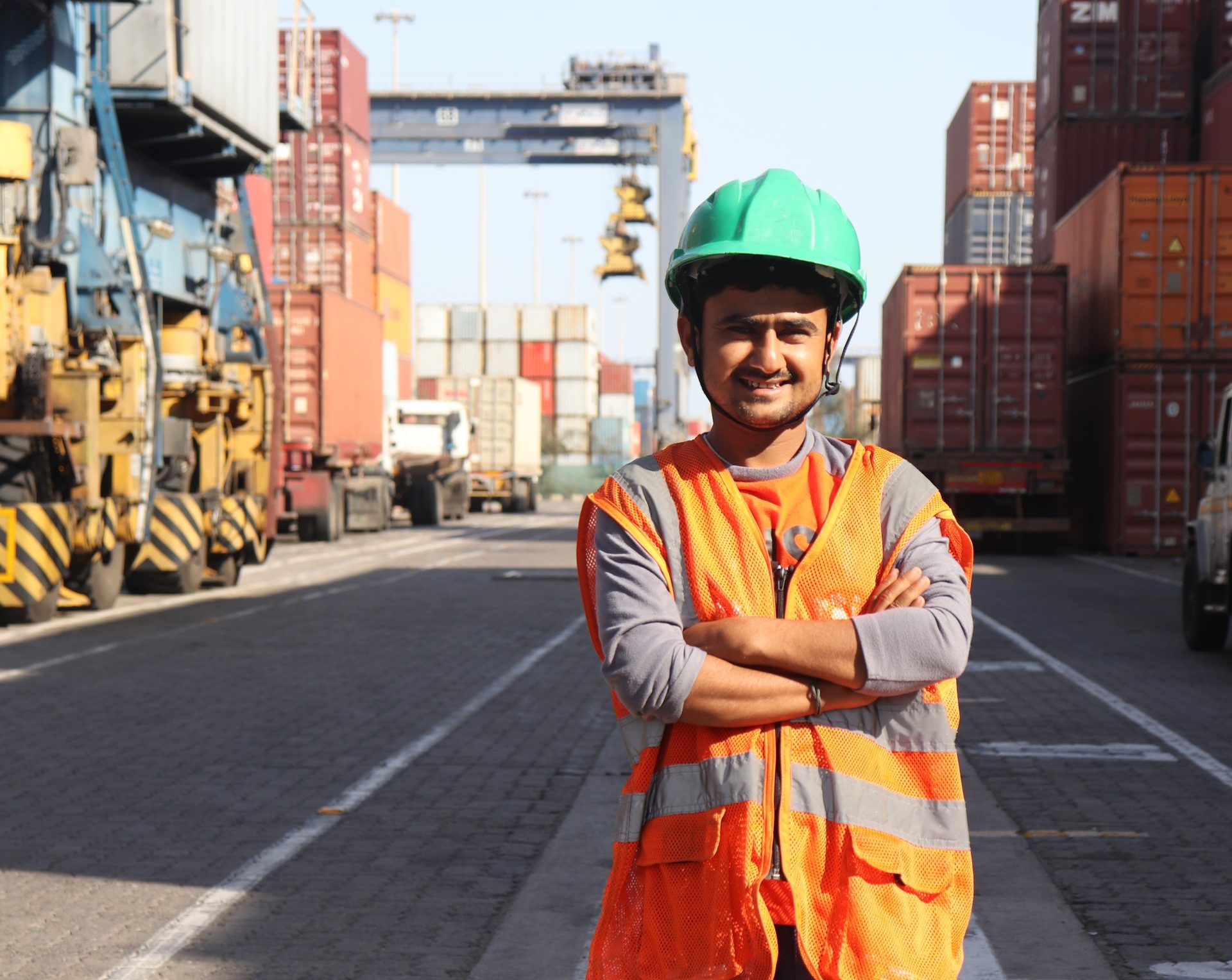 Hard hat, High-visibility clothing, Road surface, Smile, Helmet, Workwear, Tire, Infrastructure, Orange, Building