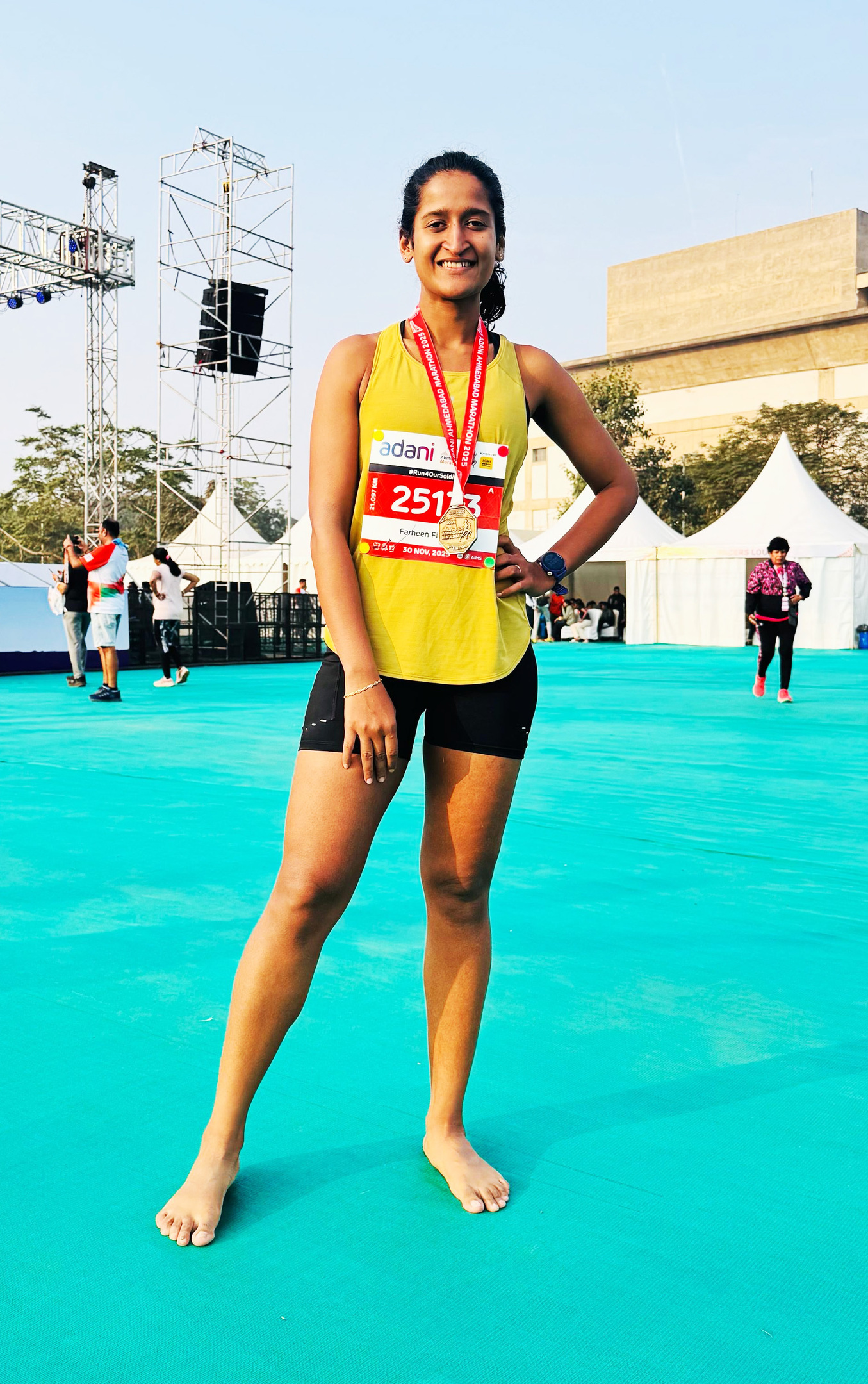 Smiling woman, Farheen F., wearing a marathon medal and bib (2513) from Adani Ahmedabad Marathon.
