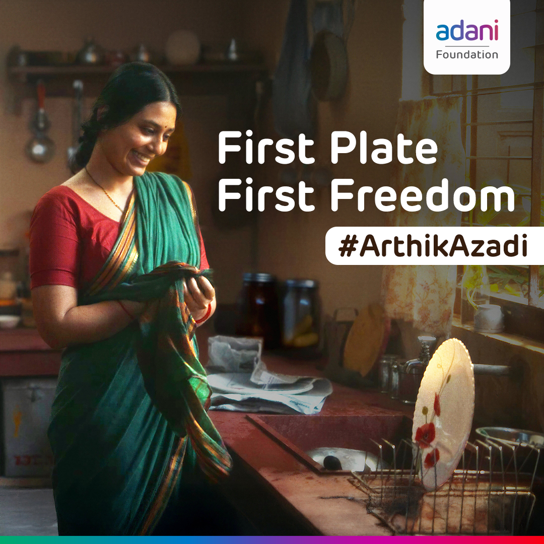 Smiling woman in kitchen with "First Plate First Freedom #ArthikAzadi" text and Adani logo.