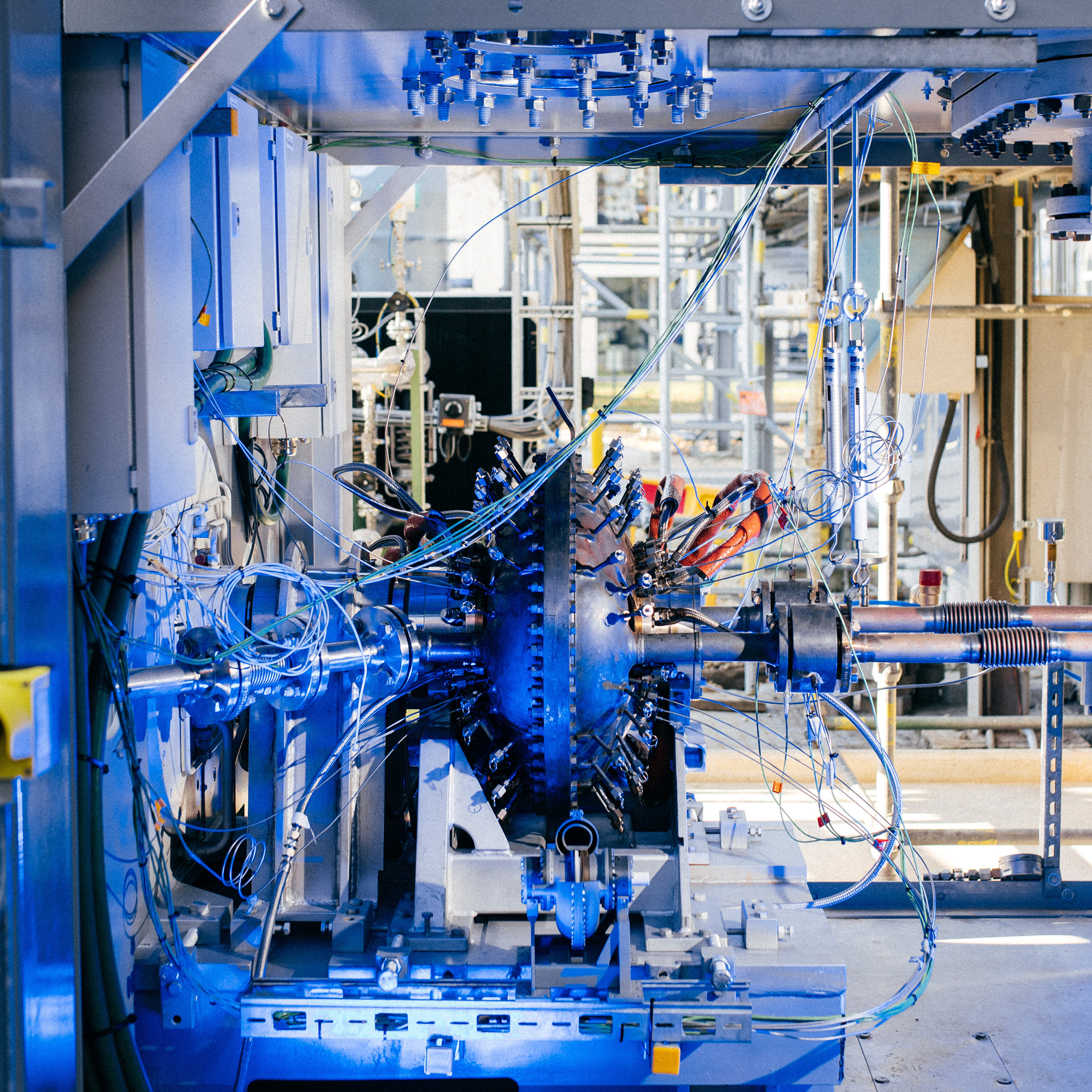 Blue-lit industrial machinery with intricate wiring, pipes, and components.