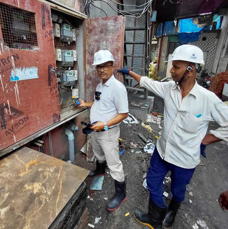 Two men in hard hats inspecting electrical meters.