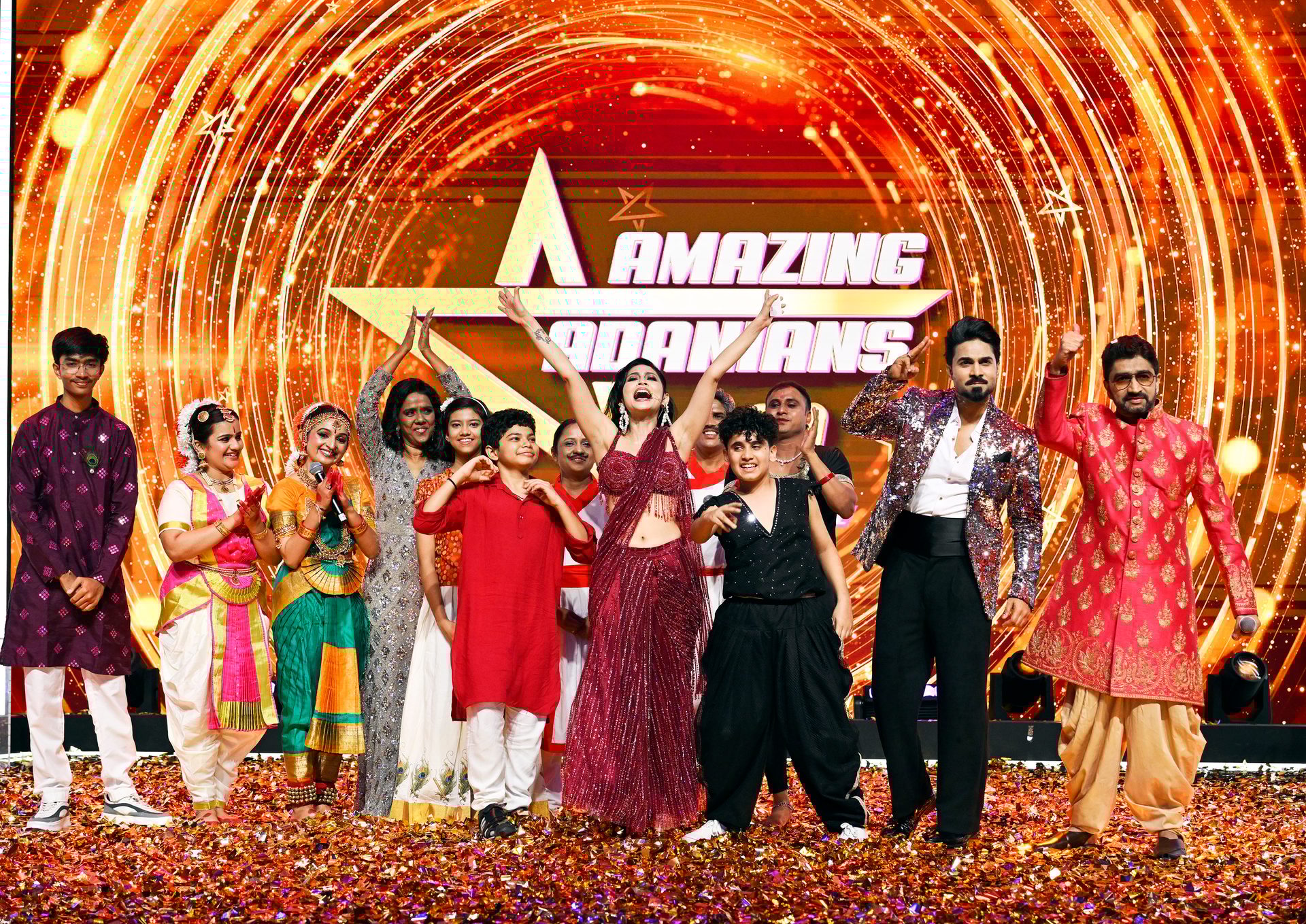A group celebrating on a confetti-covered stage with a sparkling "Amazing Dancers" backdrop.