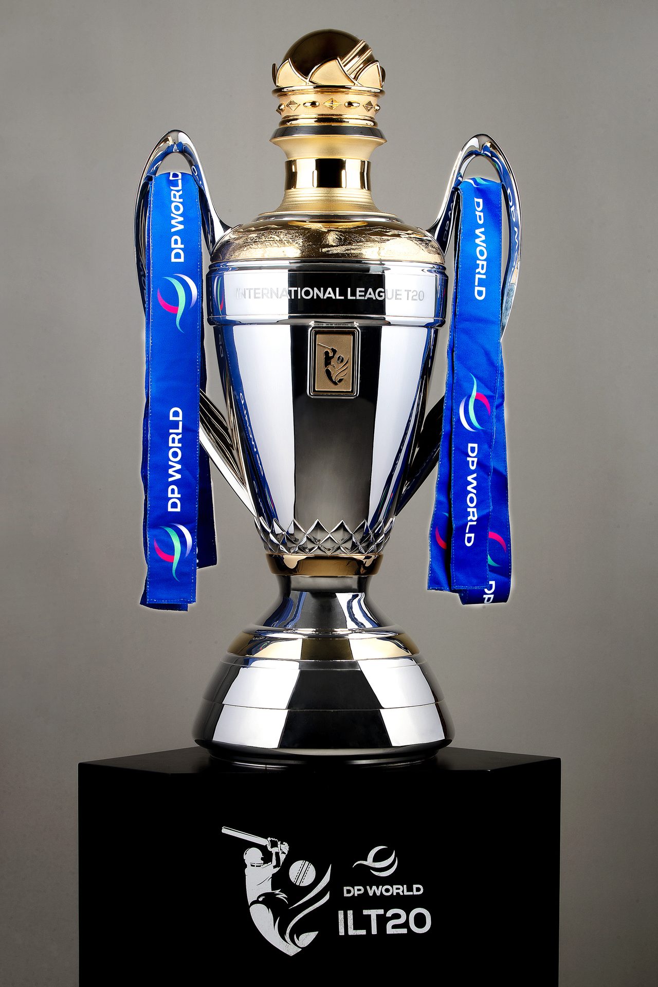 DP World ILT20 cricket trophy, silver and gold, with blue ribbons, on a black stand.
