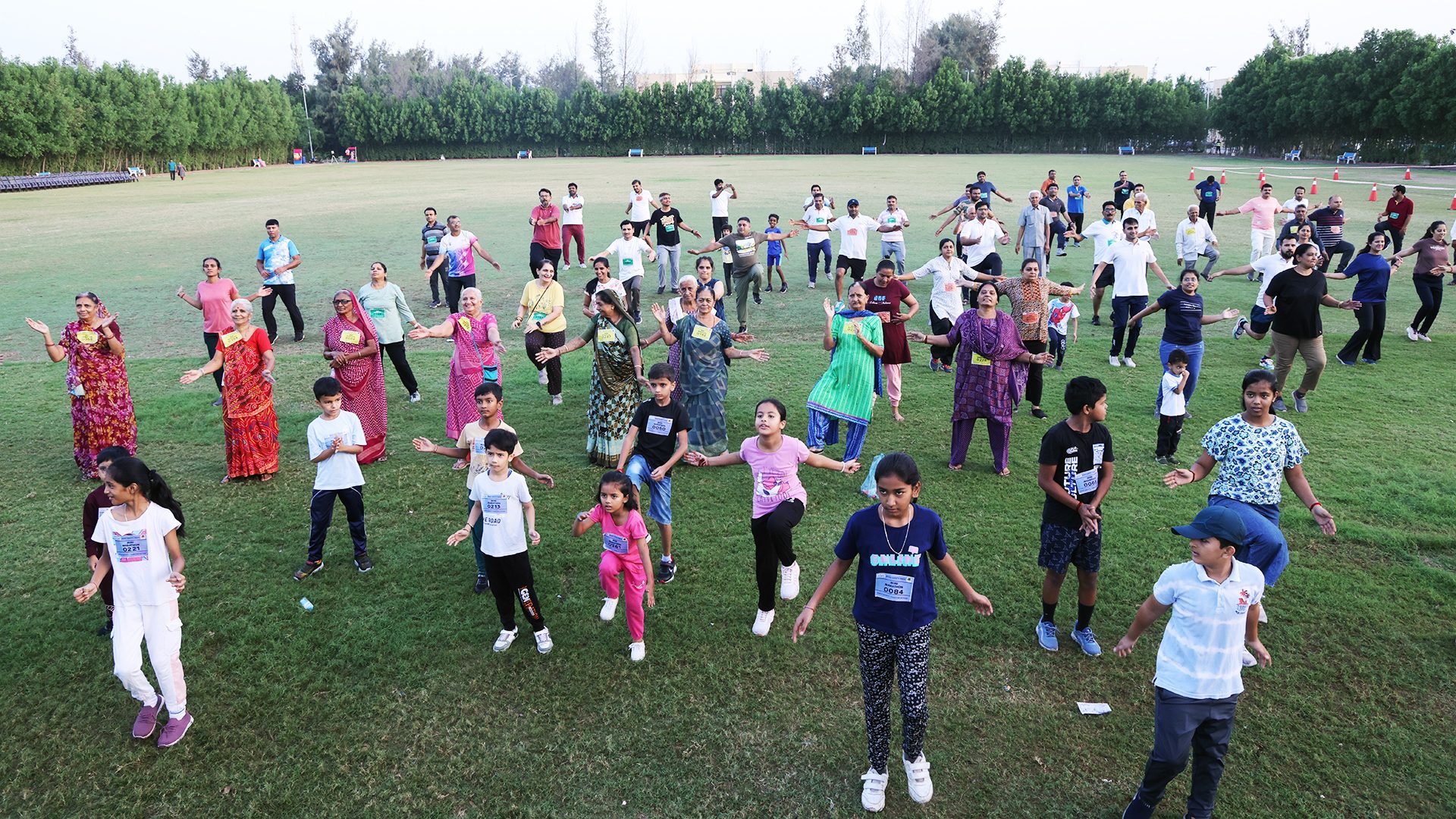 Multigenerational group exercising outdoors on a grassy field.
