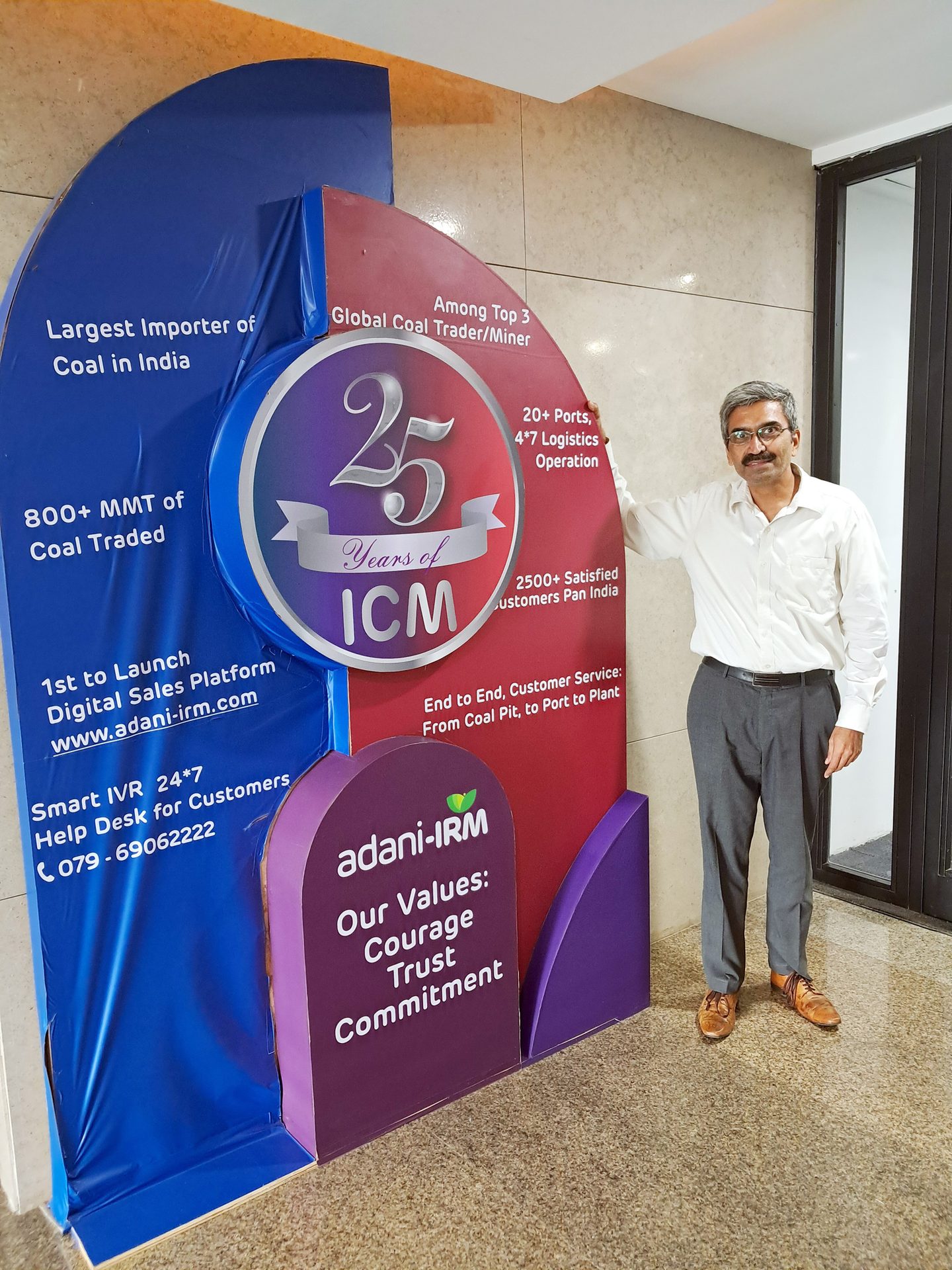 Man next to an Adani-IRM display board celebrating 25 years of ICM and coal business achievements.