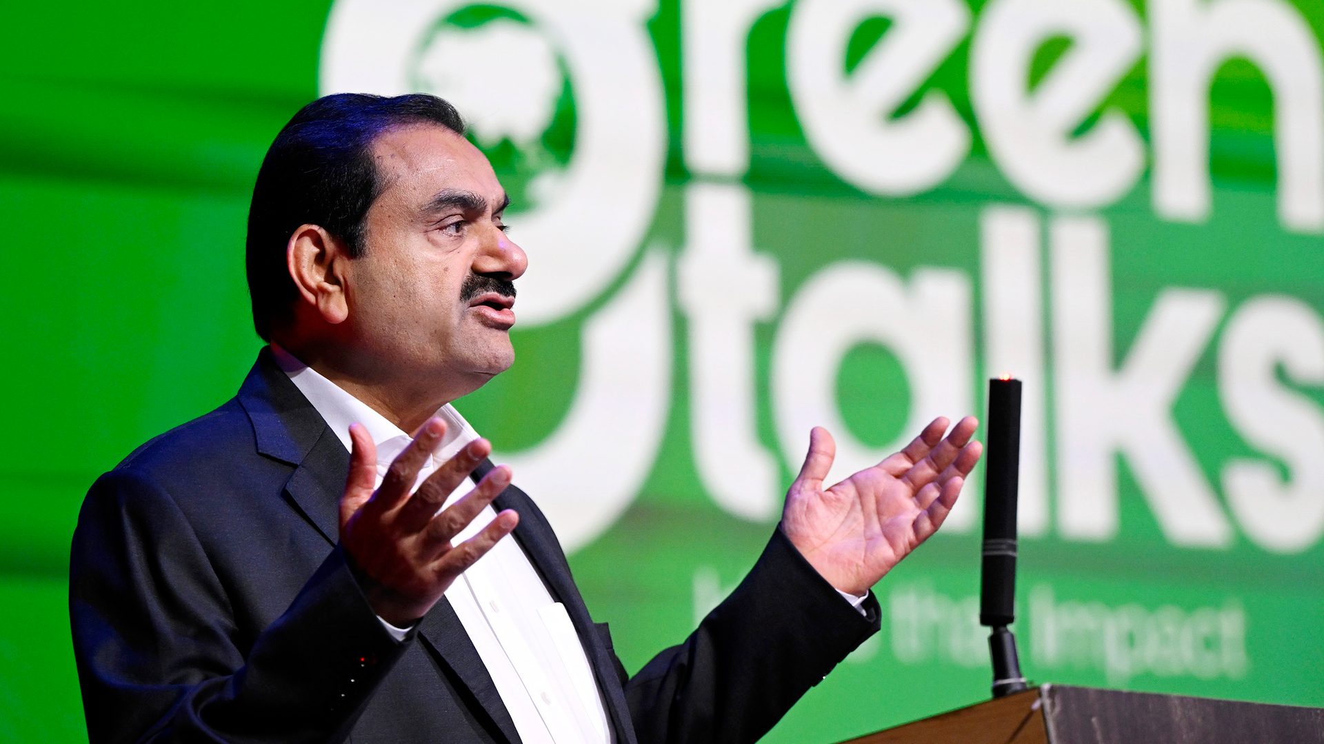 Gautam Adani speaking at a "Green Talks" event, gesturing with his hands.