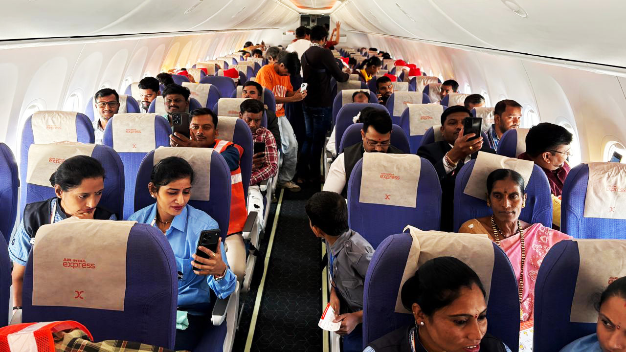 Air India Express plane interior with many passengers, several using phones.
