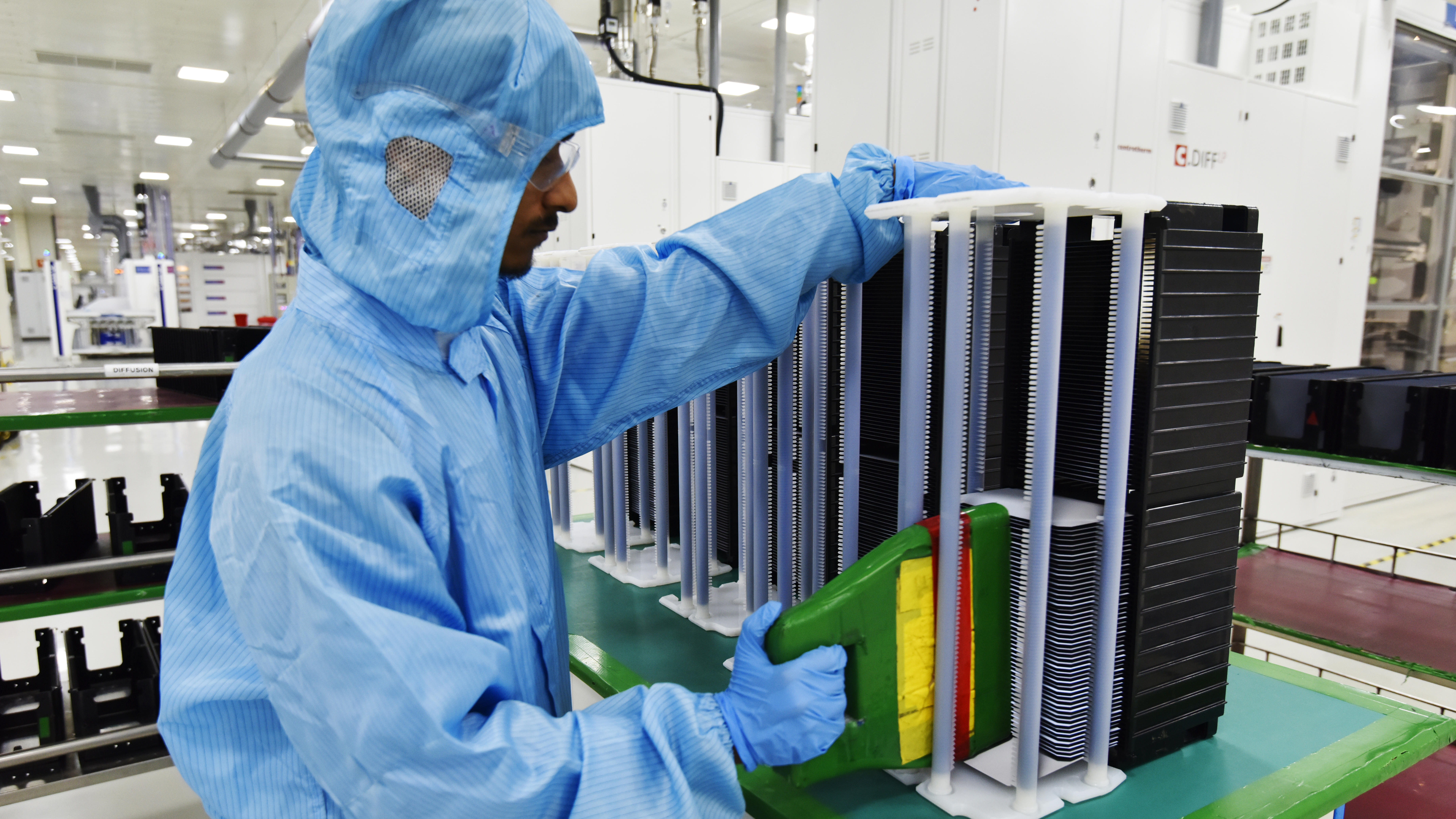 A worker in a cleanroom suit handles wafers in a cleanroom.