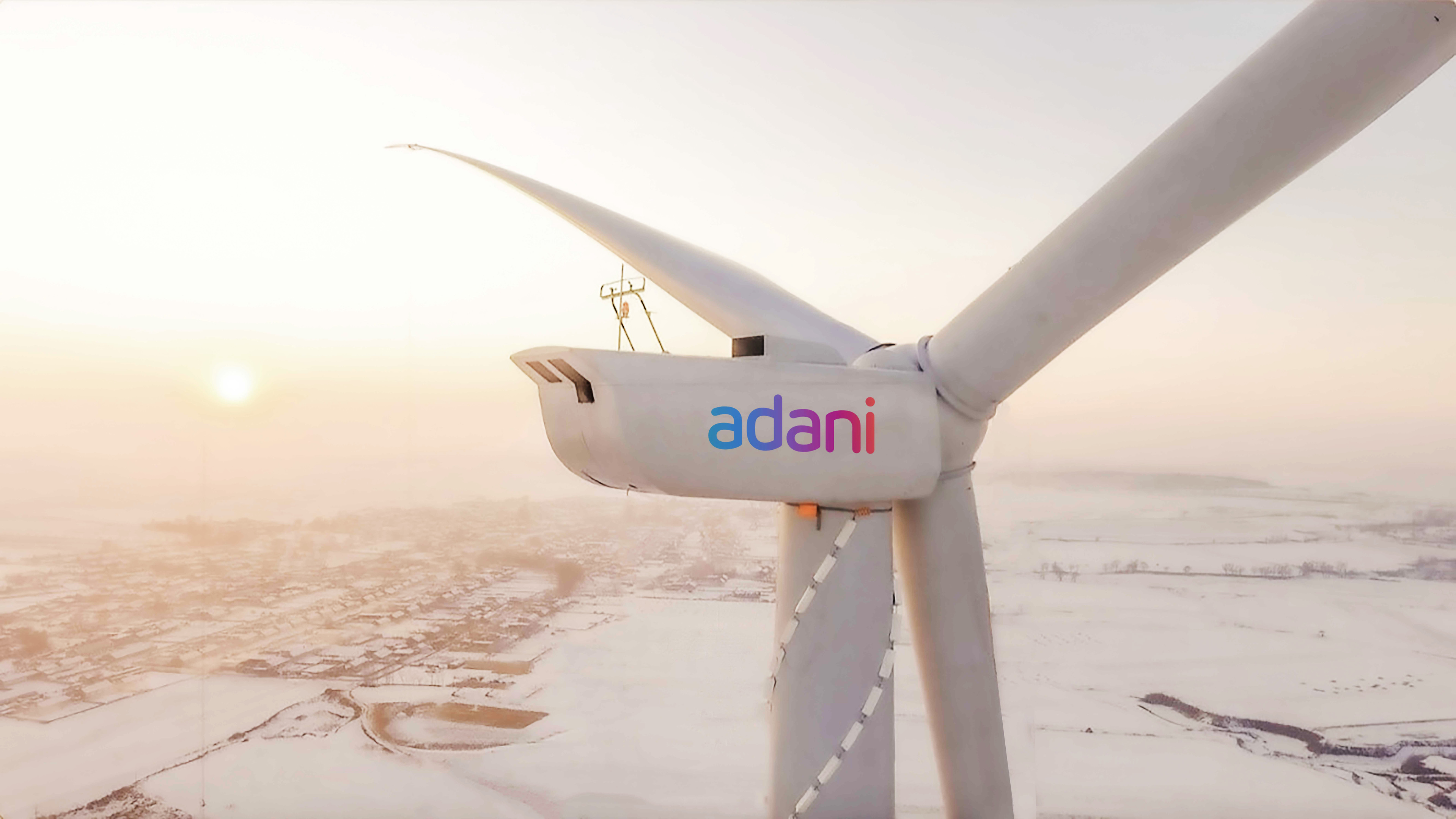 Adani wind turbine with logo, in snowy landscape under a bright sun.