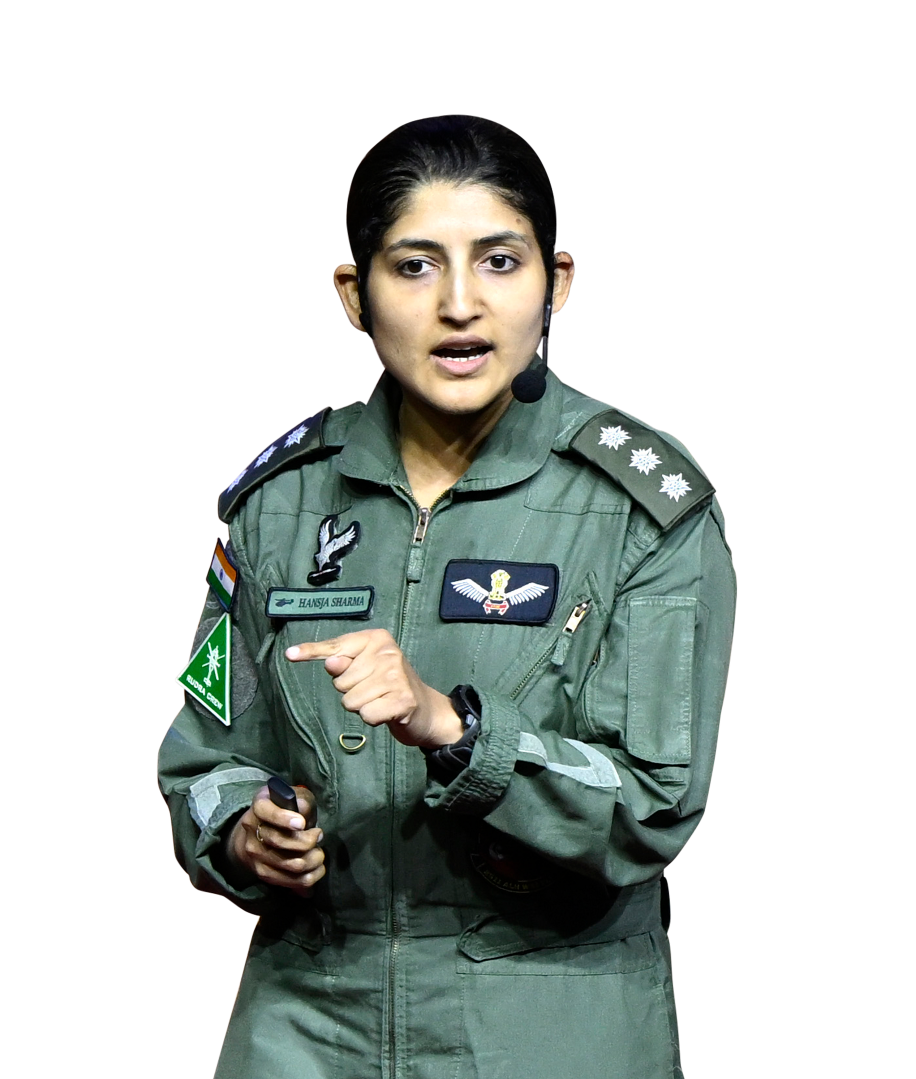 Female Indian Air Force pilot Hansaja Sharma in flight suit, speaking and pointing during an event.