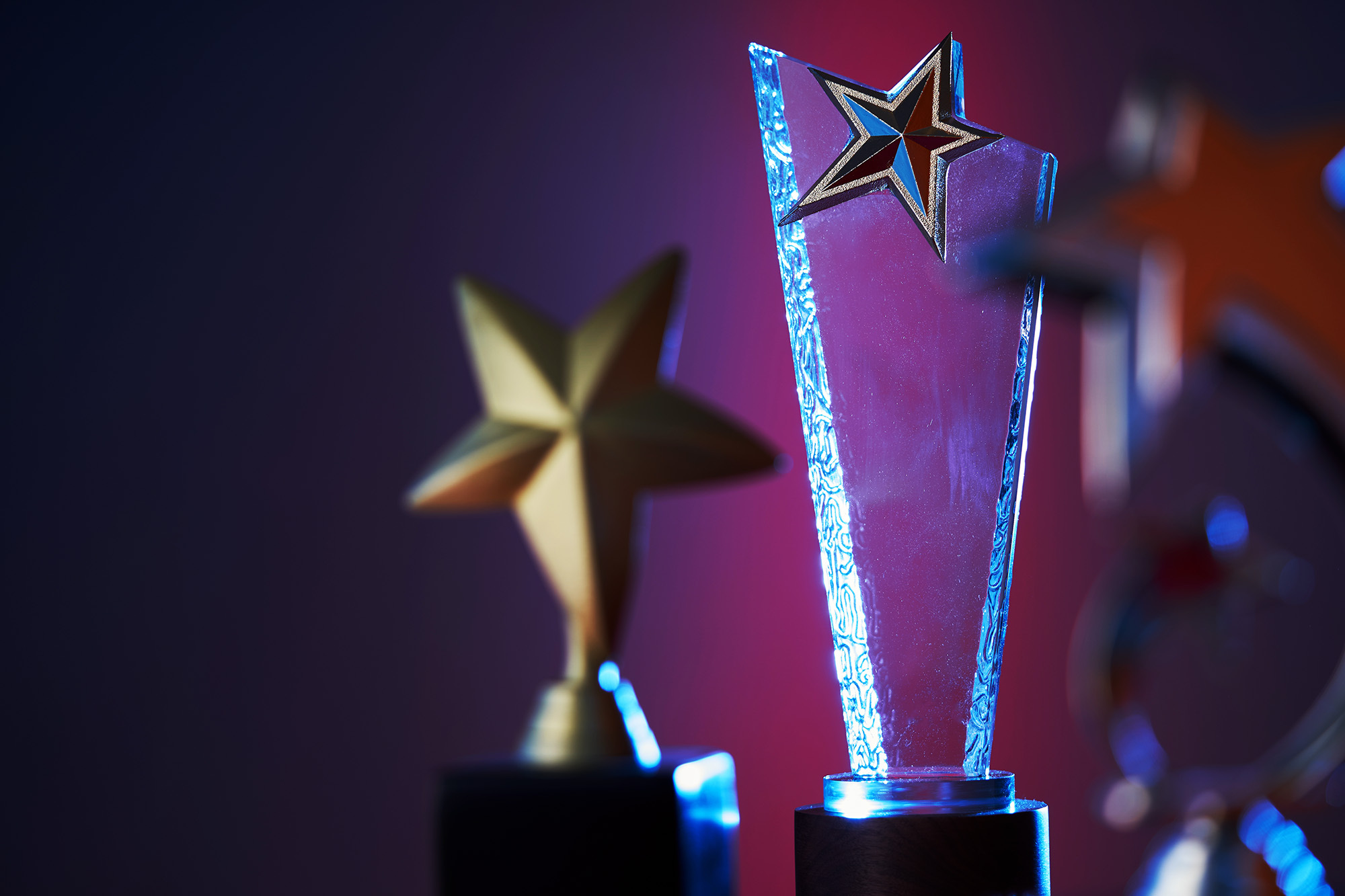 Clear, blue-lit star award foreground, golden star blurred background.