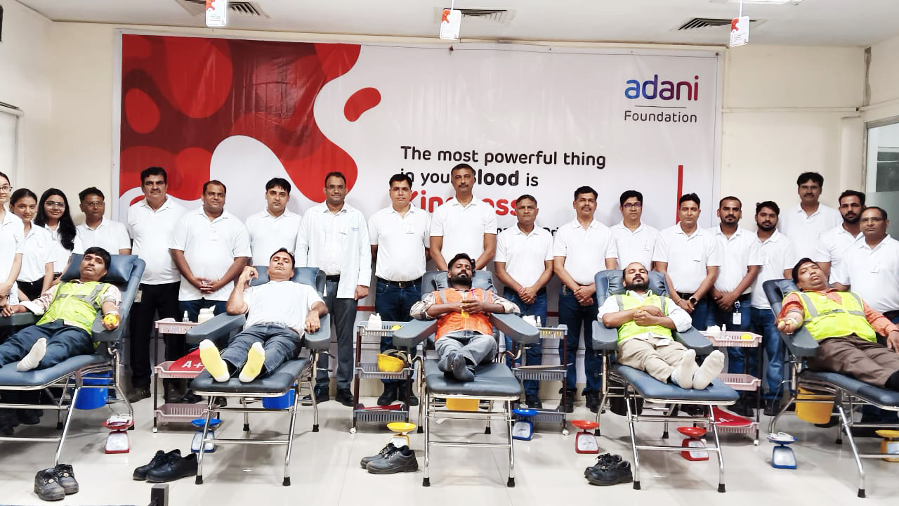 A group of people, some standing and others donating blood in chairs, at an Adani Foundation blood drive.