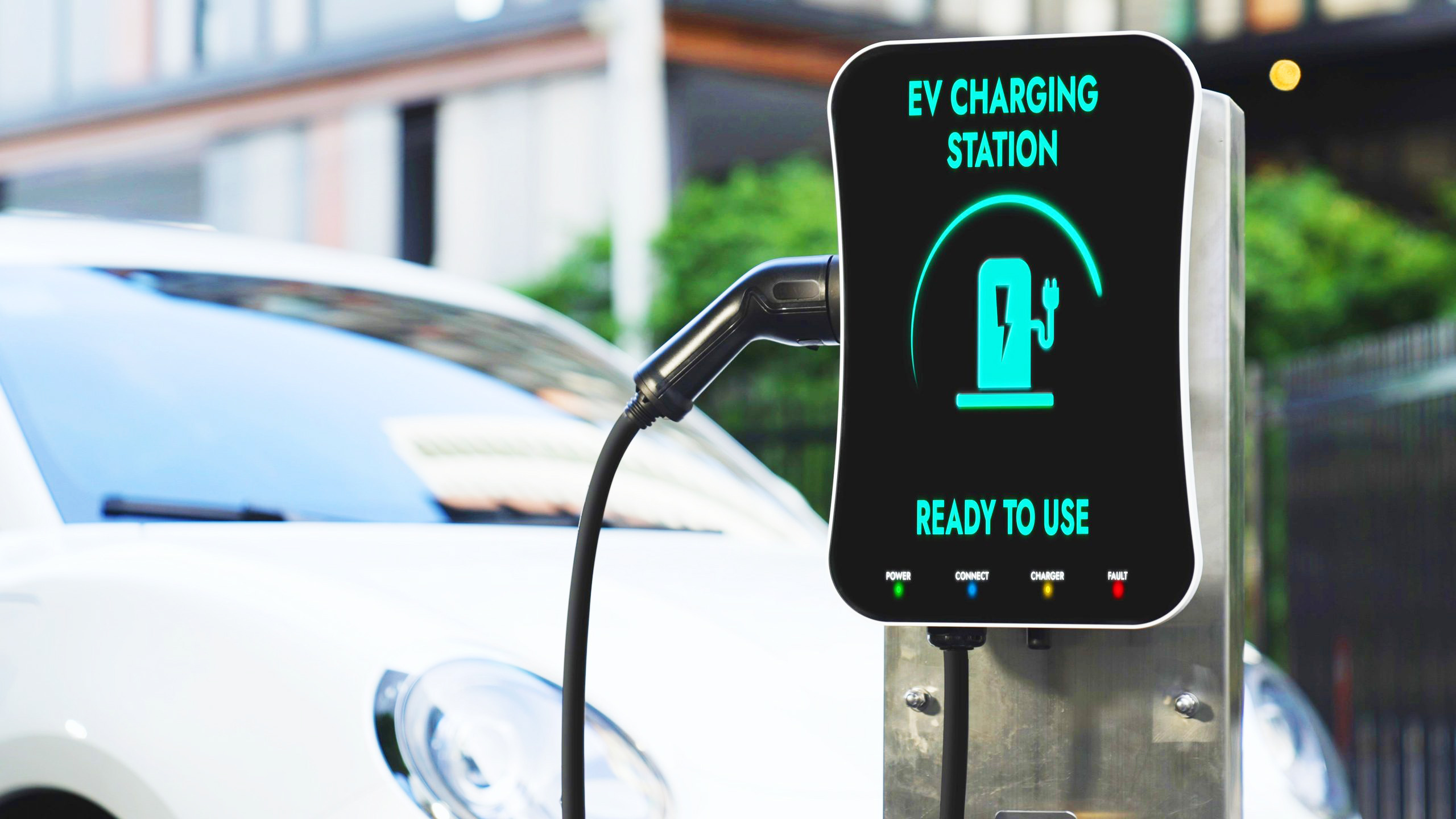 An electric car is connected to an EV charging station, displaying 'Ready to Use'.
