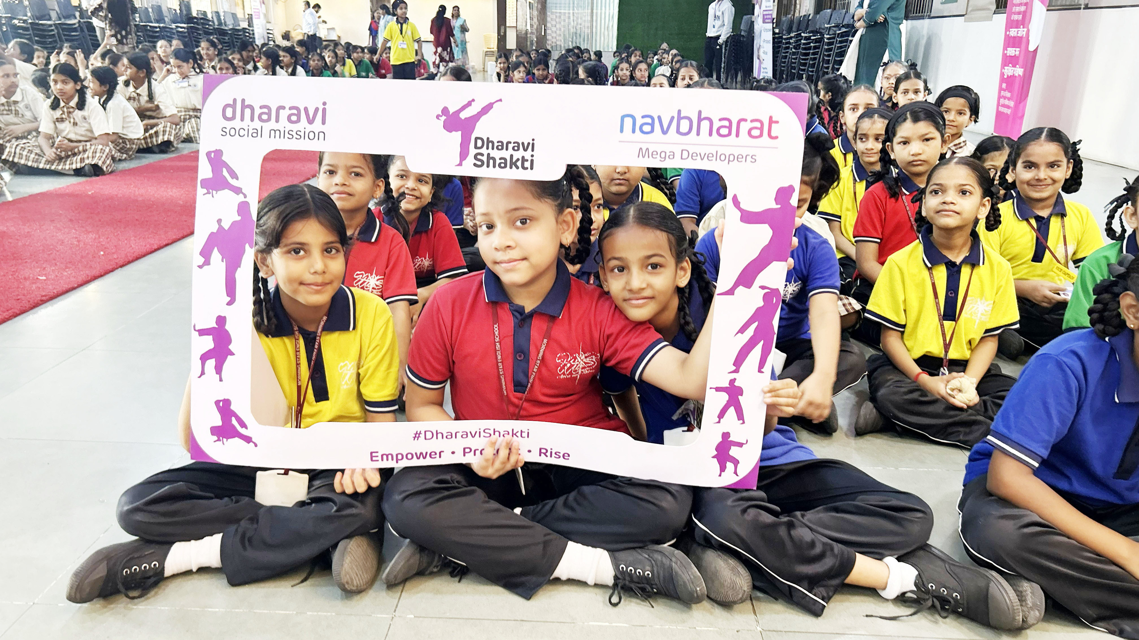 Girls from Dharavi Shakti program posing with a promotional frame showcasing martial arts poses.