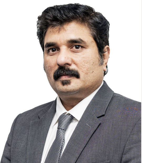 Headshot of a man with dark hair, mustache, and goatee, wearing a gray suit and patterned tie.