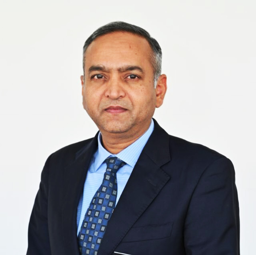 Headshot of a man in a dark suit and blue patterned tie against a white background.