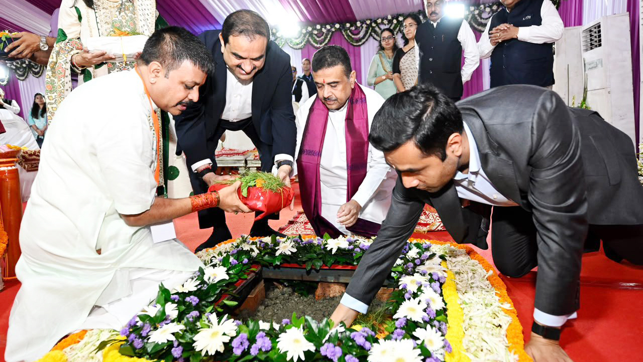 Men participate in a ceremonial groundbreaking, placing items into a decorated pit.