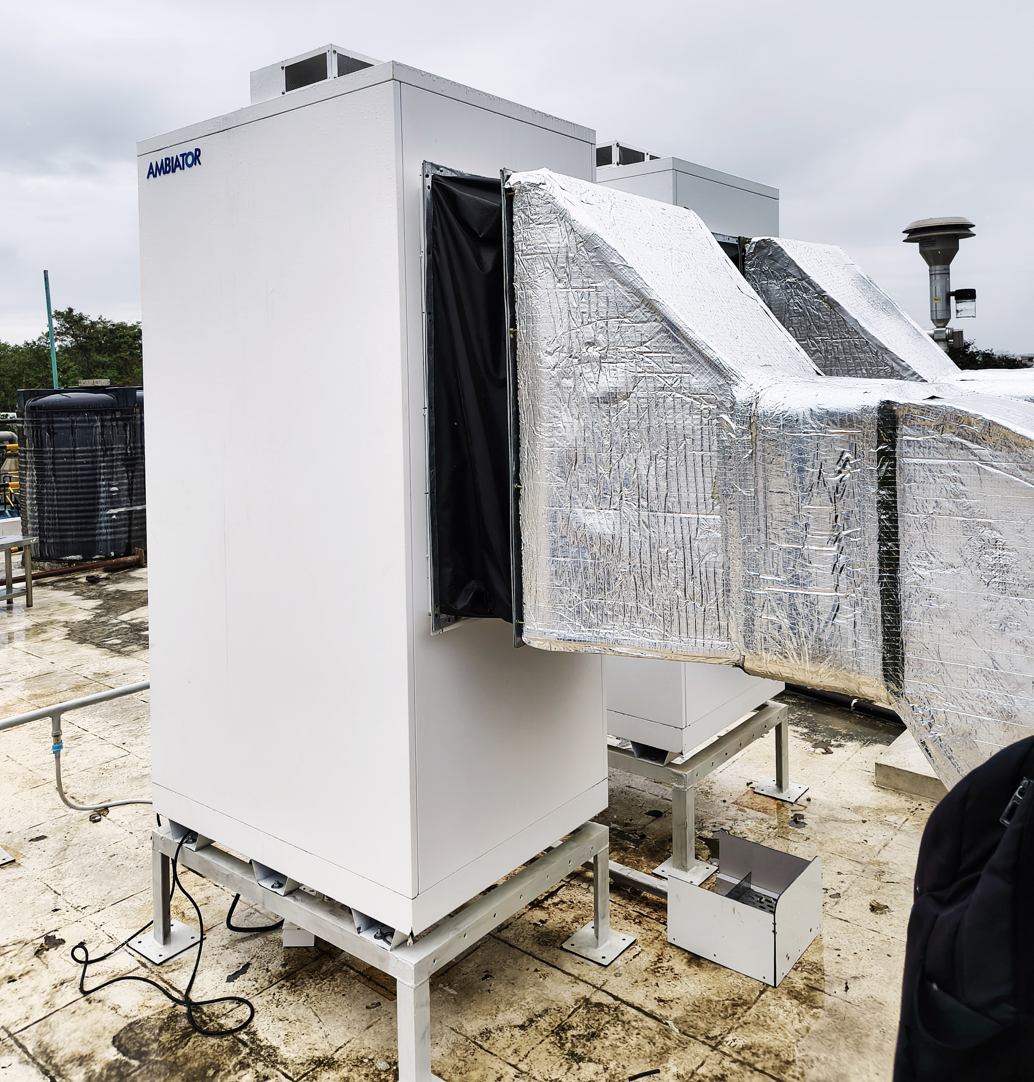 White AMBIATOR industrial unit and silver insulated ducts on a rooftop.