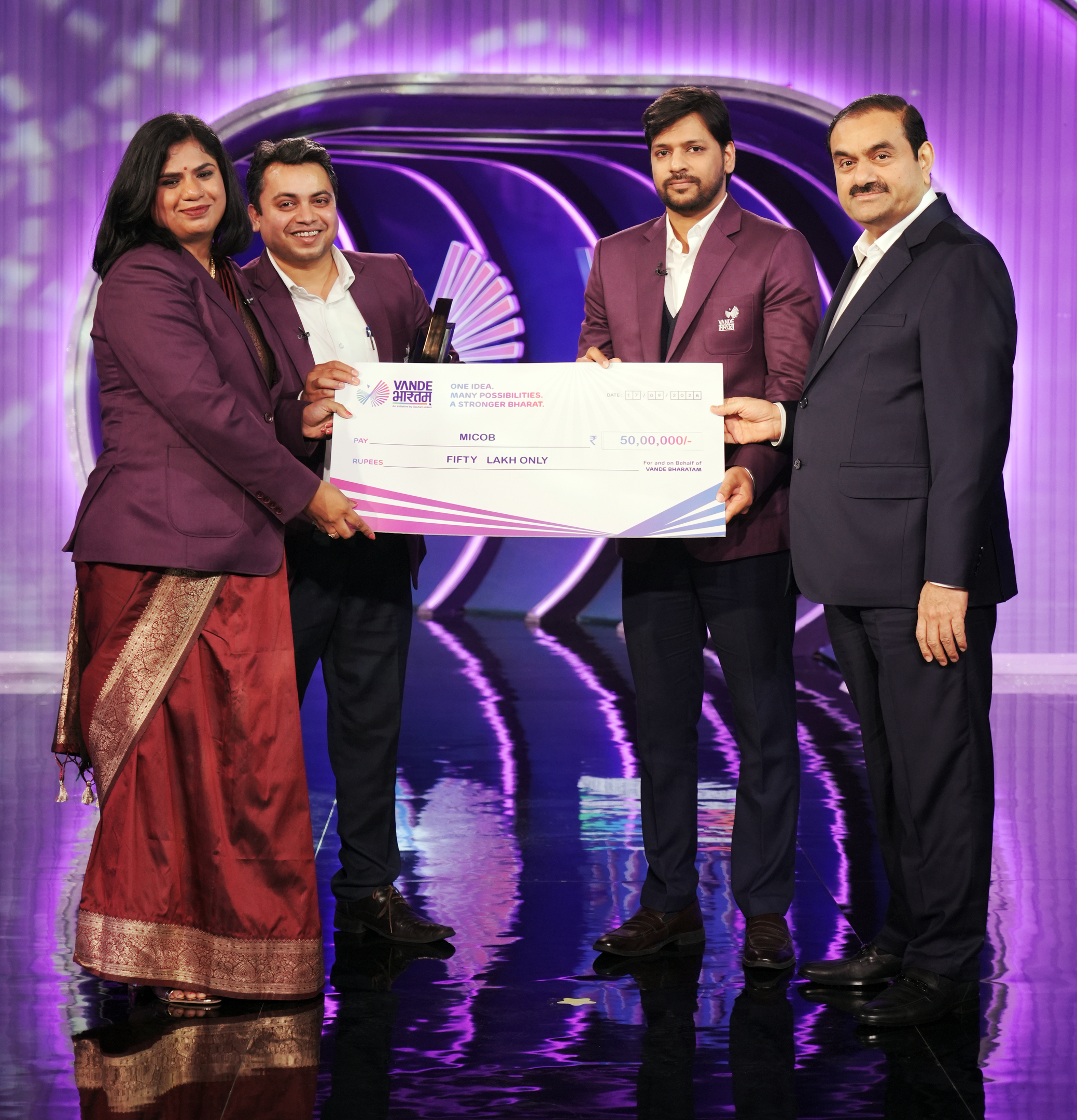 Four individuals, including Gautam Adani, present a large ceremonial check for fifty lakh rupees from Vande Bharatam.