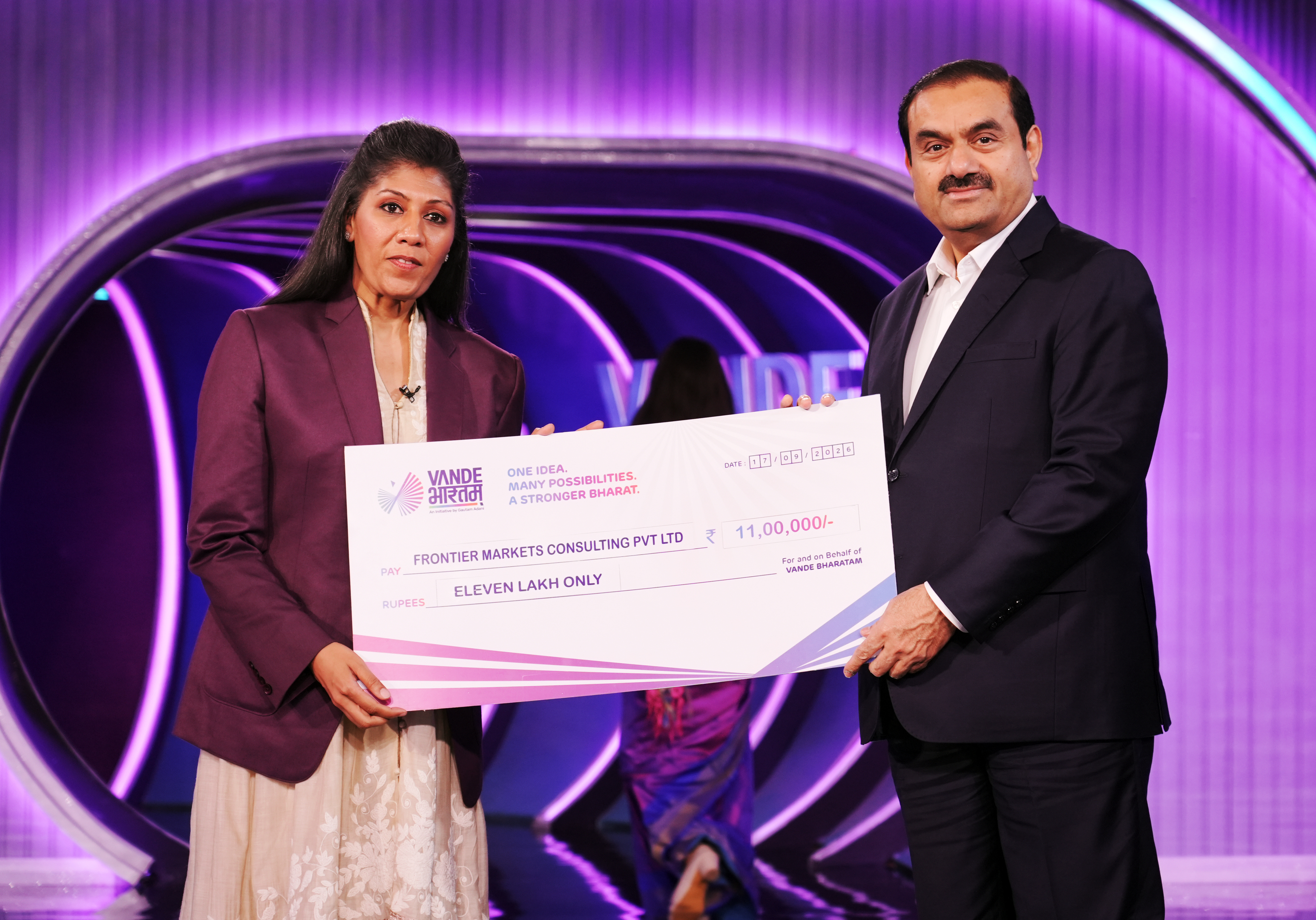 Gautam Adani and a woman holding a large check for "Eleven Lakh Only" from Vande Bharatam.