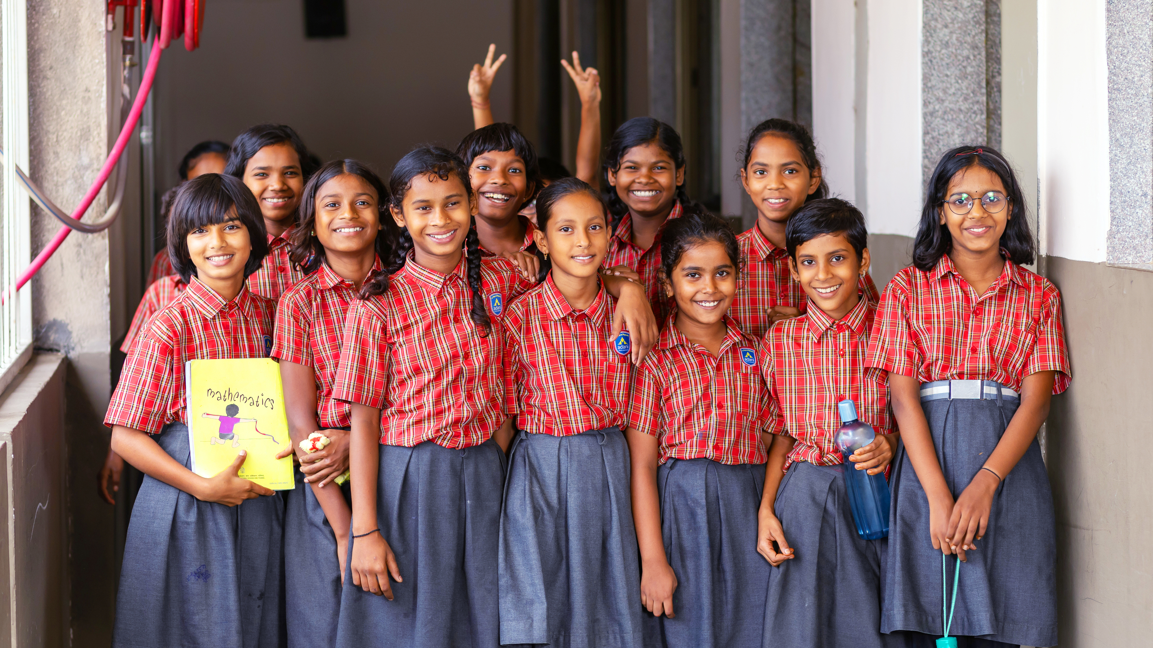 A cheerful group of diverse schoolgirls in plaid uniforms posing and smiling together.