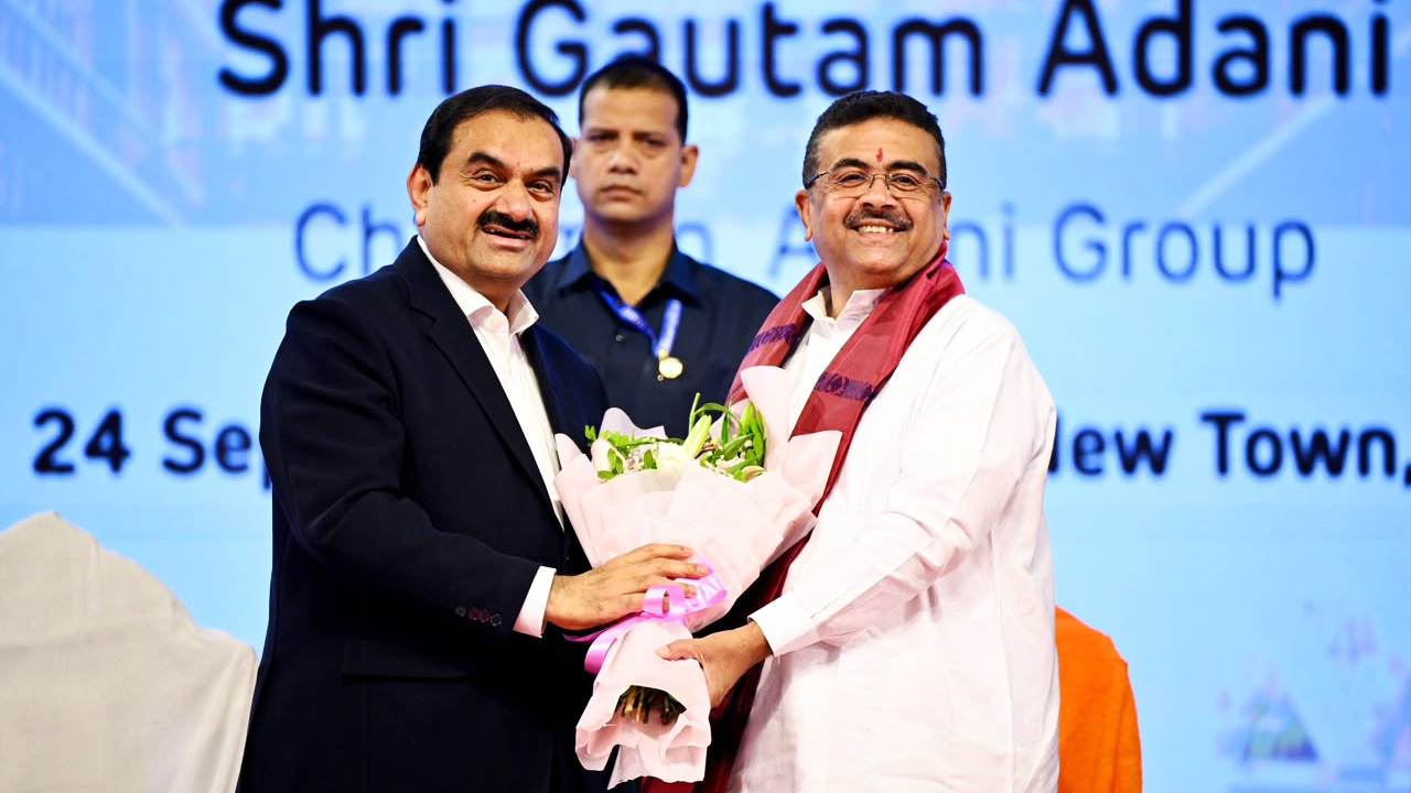 Gautam Adani receives a bouquet at an event, with another man in the background.