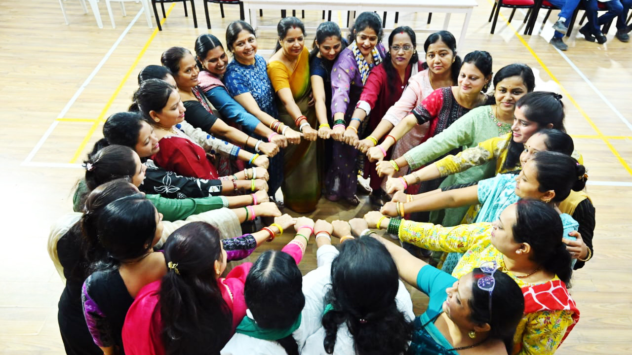 A diverse group of women forming a circle, holding wrists, symbolizing unity and togetherness.