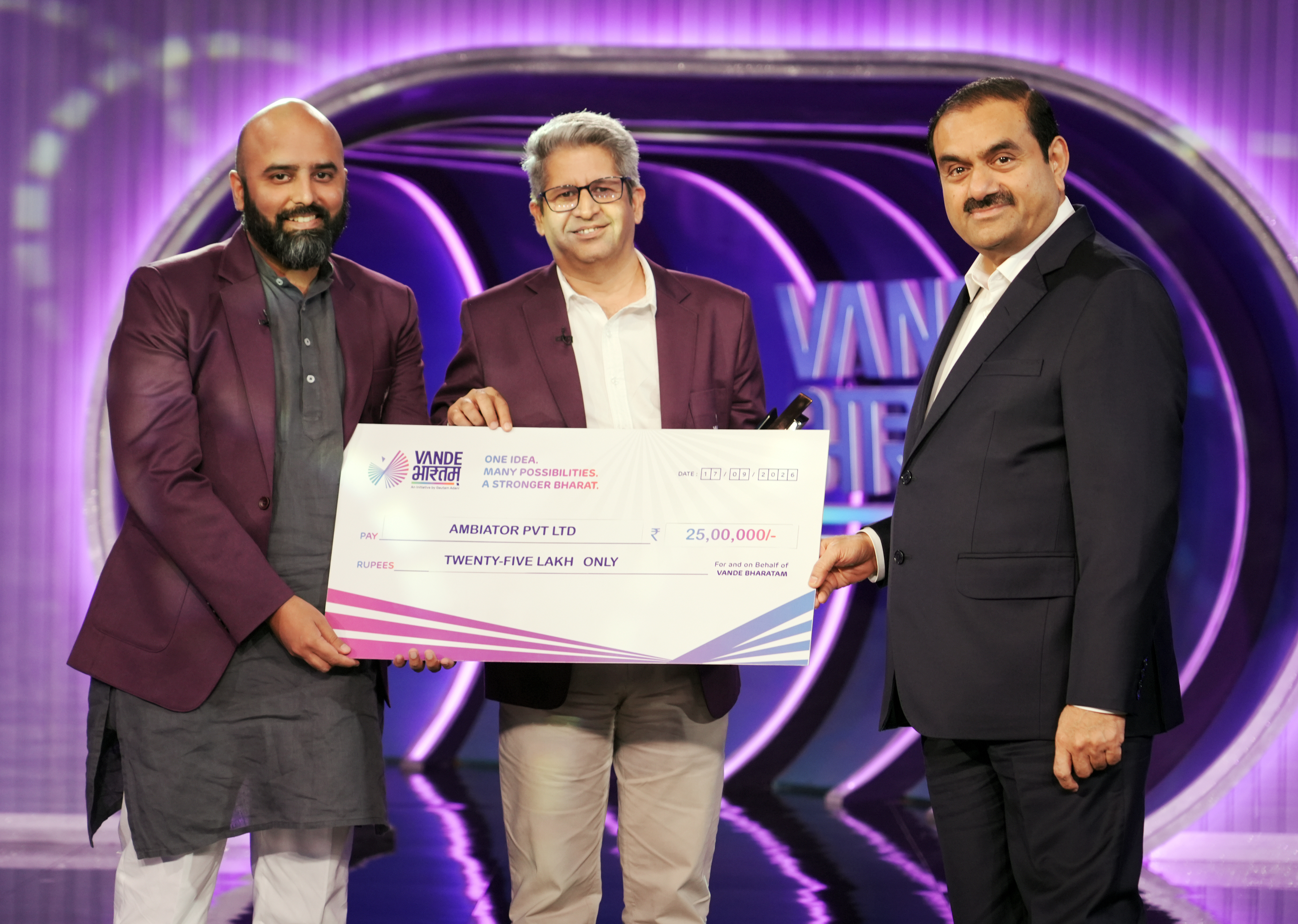 Three men, including Gautam Adani, on stage with a giant check for Ambator Pvt Ltd, ₹25 Lakh.