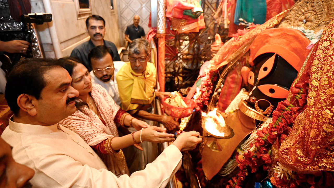 Gautam and Priti Adani performing a ritual at a Kali temple with a priest.