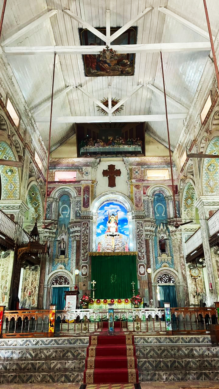 A vibrant and ornate church interior with a detailed altar, religious artworks, and a red carpet.