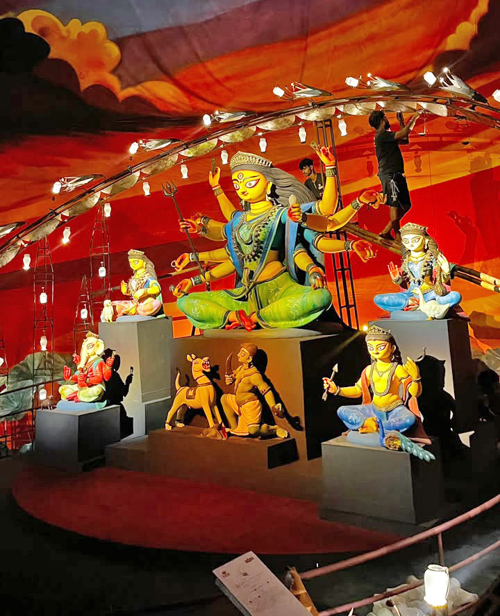 Durga Puja display: Colorful Hindu deities, including Goddess Durga, on platforms under festive lights.