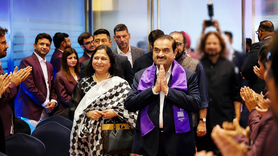 Gautam Adani and Priti Adani are welcomed by people clapping.
