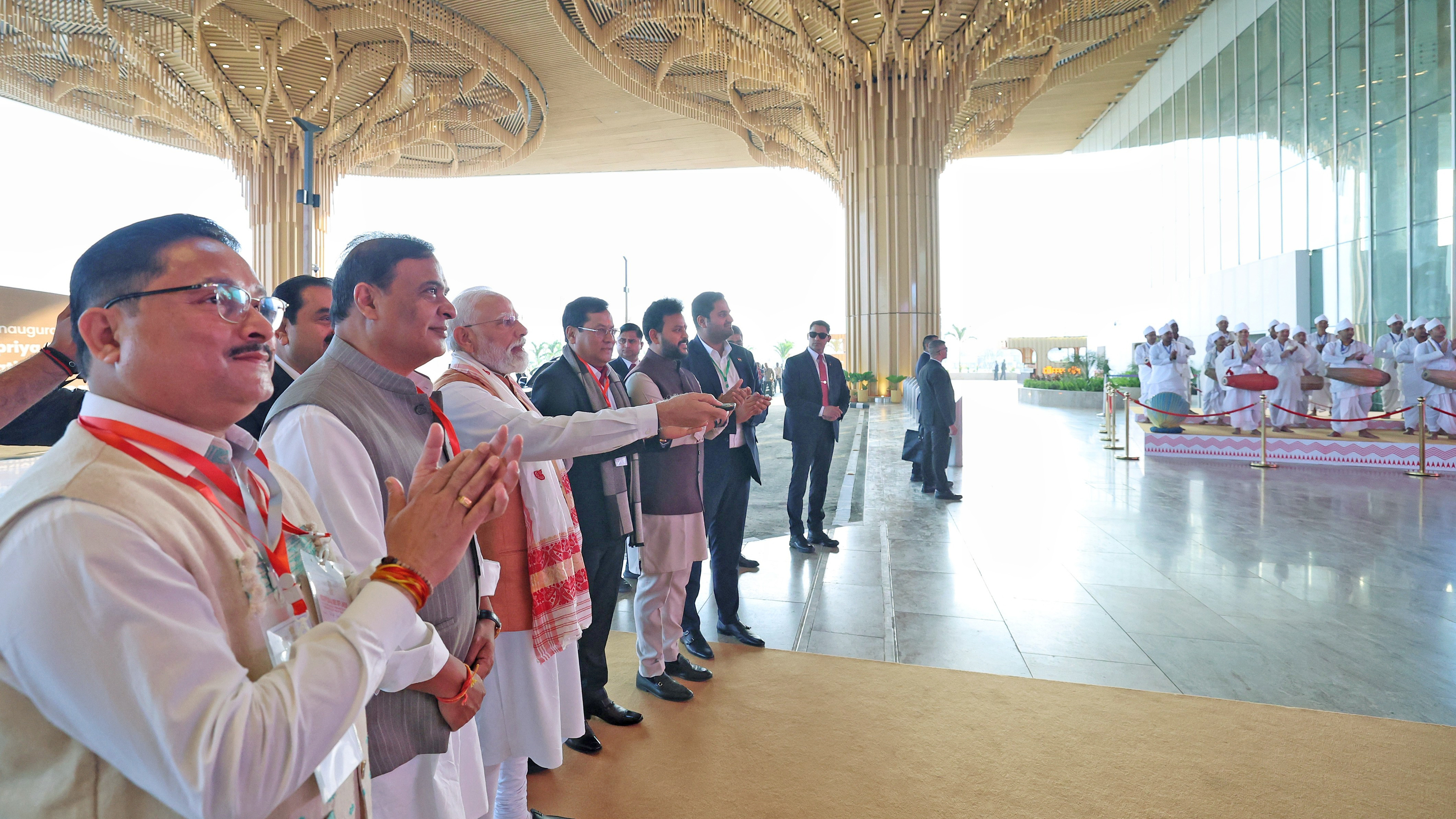 PM Modi and other officials watching traditional drummers inside a modern building.