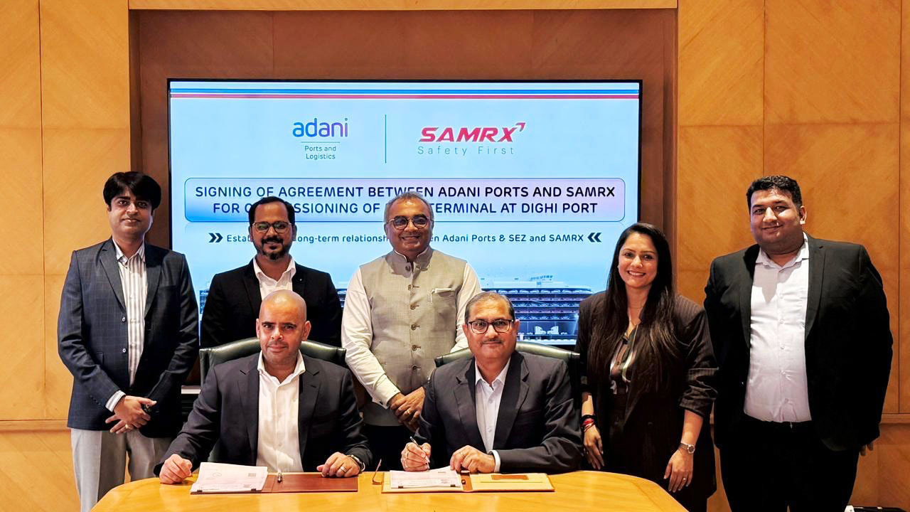 Six people at an agreement signing ceremony between Adani Ports and SAMRX.