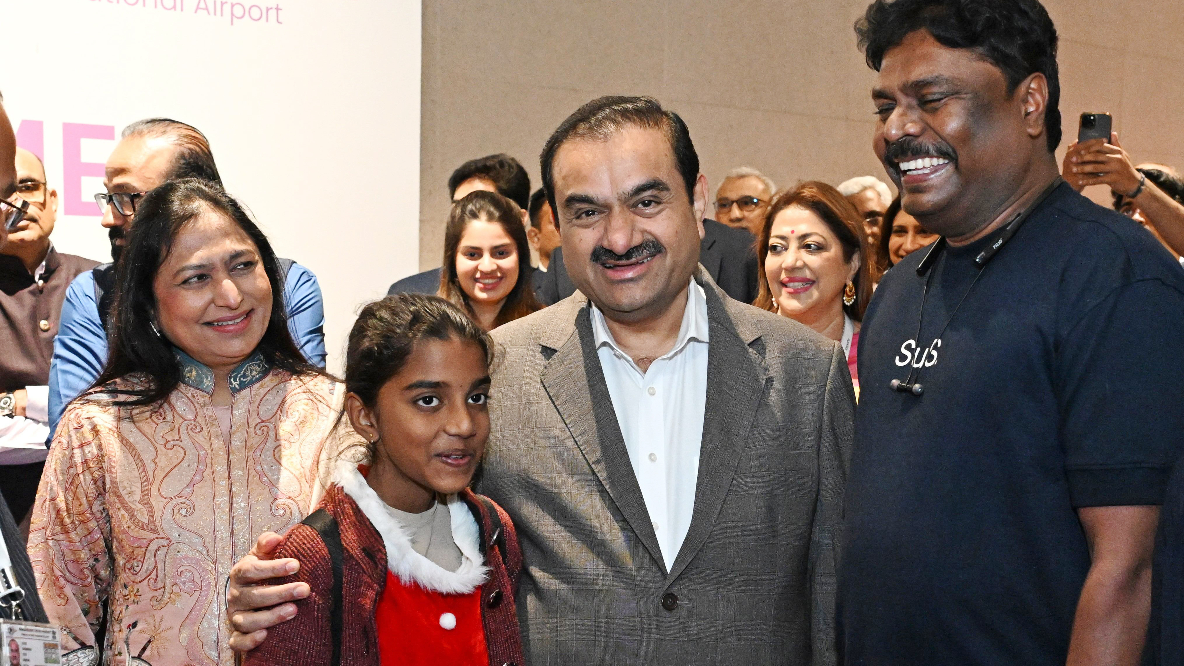 Gautam Adani, a woman, a girl, and a man smile broadly for a photo at an event.