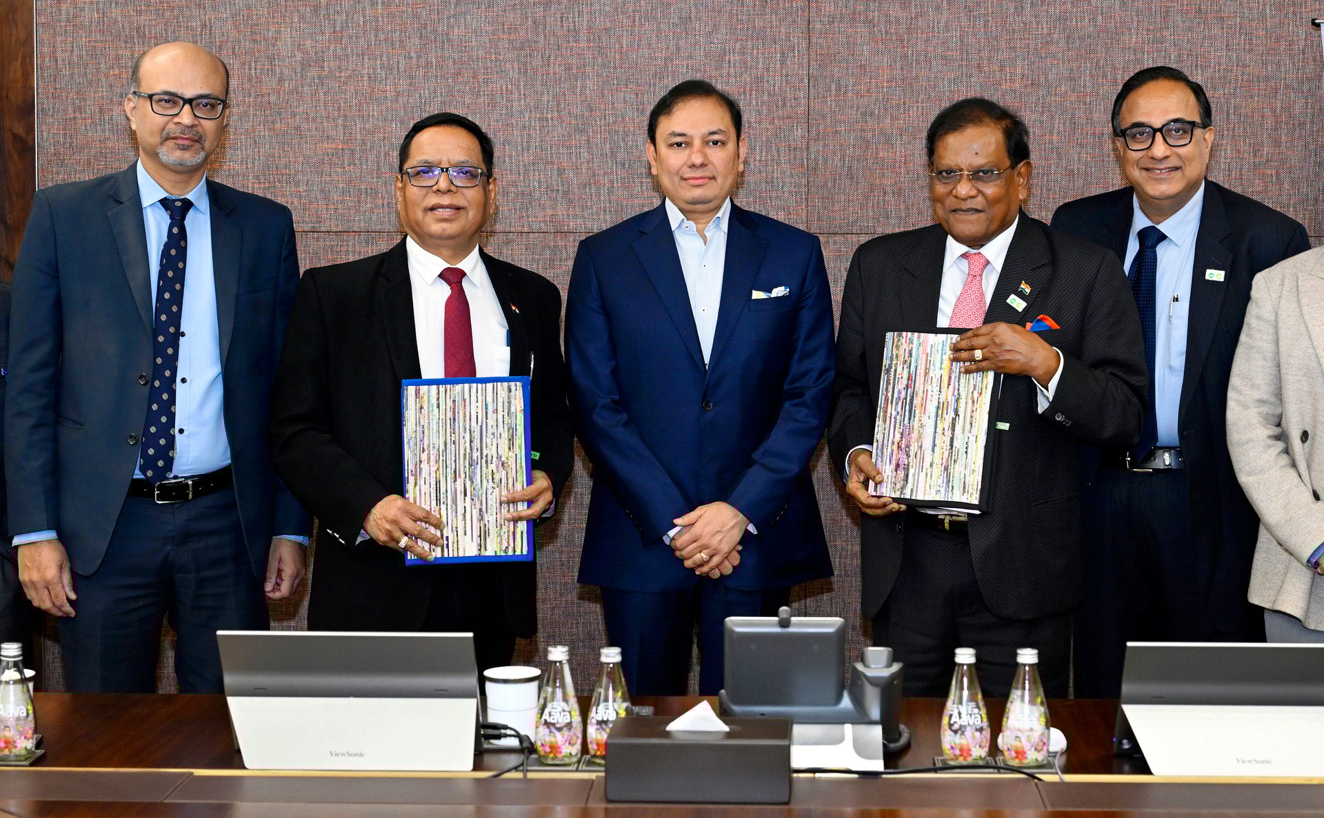 Six men in suits posing with colorful documents at a business meeting.