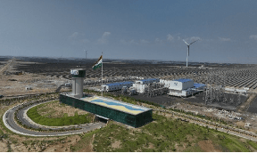 Indian renewable energy plant with vast solar panels and wind turbines.