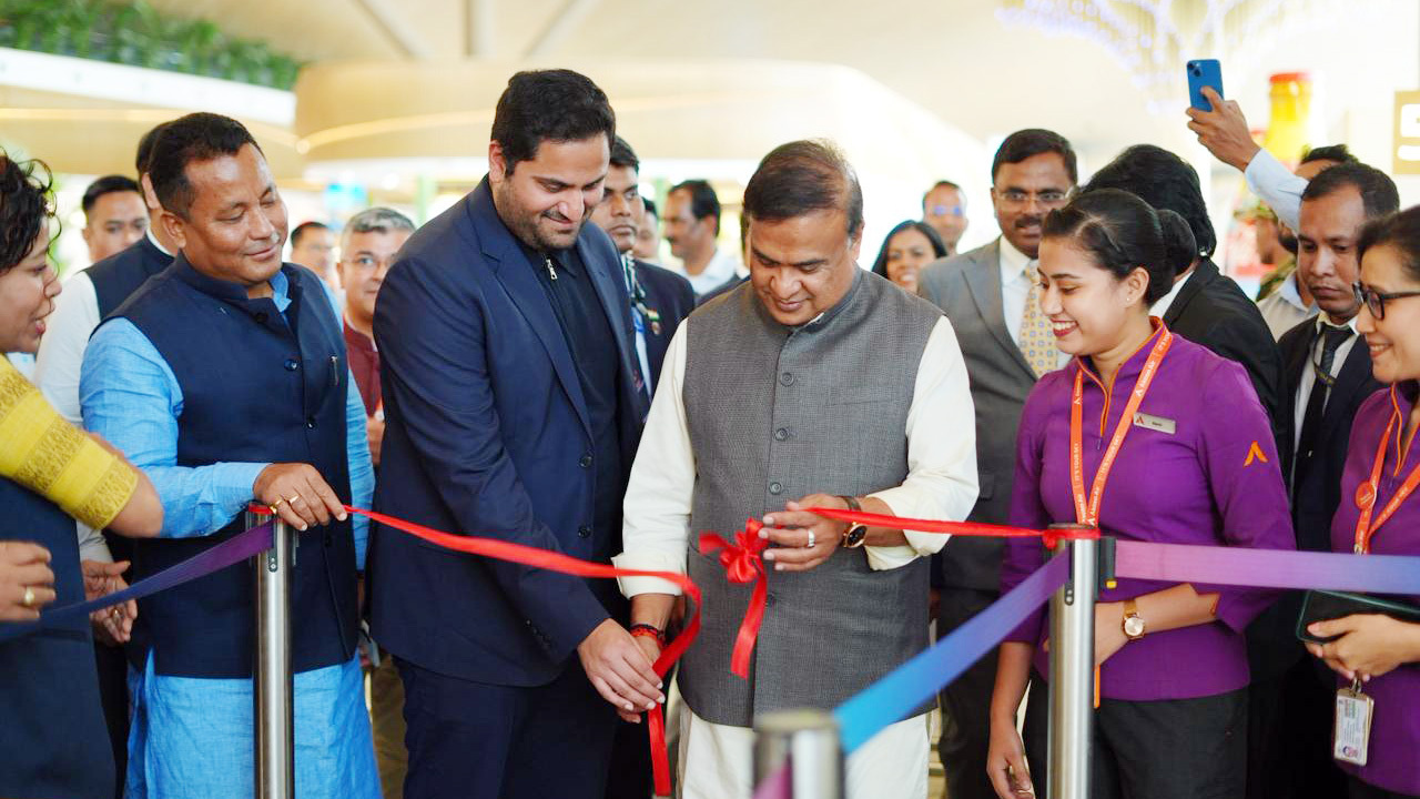 Political leaders and others cut a red ribbon at an inauguration ceremony, surrounded by attendees.