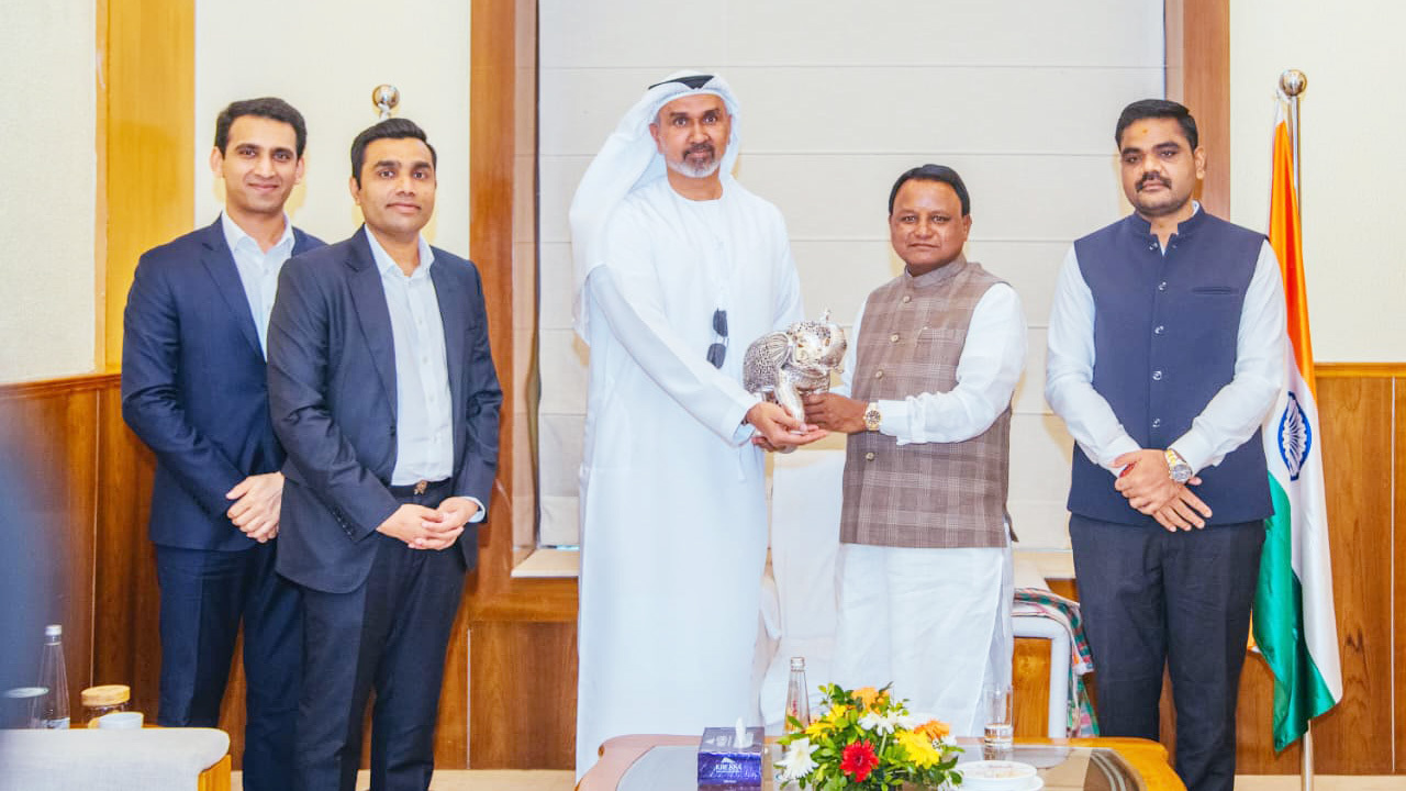 Five men, including one in traditional Arab attire, are captured exchanging a silver falcon statue.