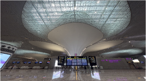 Modern airport terminal interior with a grand, wavy architectural ceiling and multiple illuminated information screens.