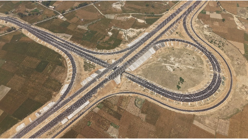 Aerial view of a complex highway interchange with multiple ramps and bridges, surrounded by farmland.